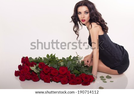 beautiful woman with dark curly hair posing with bouquet of red roses
