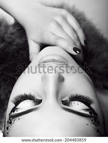 black and white fashion studio photo of beautiful girl with extravagant eyes makeup and fur