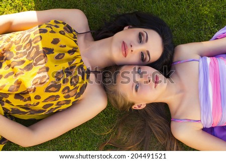 Positive portrait of beautiful mother and daughter having fun at summer garden in colorful dresses