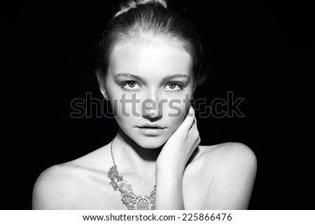 black and white fashion portrait of beautiful sensual woman with dark hair and freckles posing in the dark studio