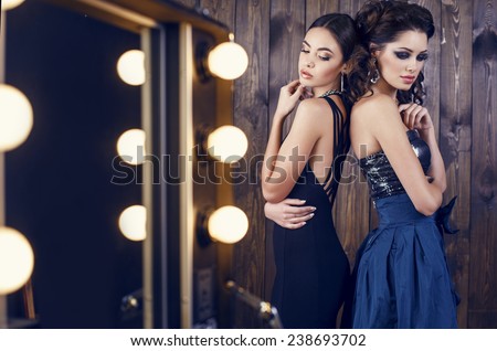 fashion studio photo of two beautiful sensual women with dark hair in luxurious dresses with bijou