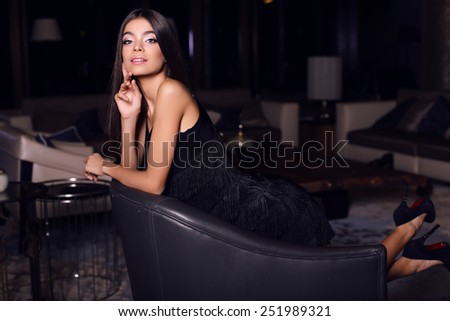 fashion indoor photo of beautiful sensual woman with long dark hair in elegant dress posing in luxury interior