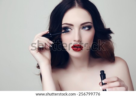 fashion studio photo of beautiful sensual woman with dark hair and bright makeup, holding mascara in hand
