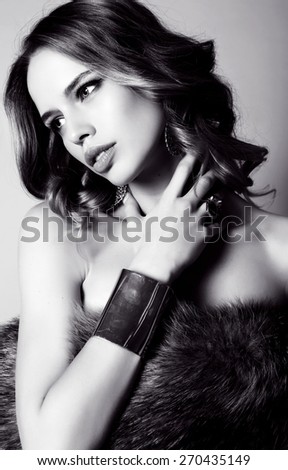 black and white fashion studio photo of beautiful sensual woman with dark hair in fur