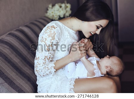 tender photo of beautiful young mother with long dark hair posing with her little adorable baby