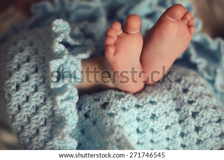 tender interior photo of cute baby feet in cozy knitted blanket