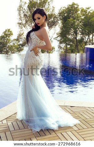 fashion studio photo of beautiful sensual woman with dark hair in elegant gold dress
