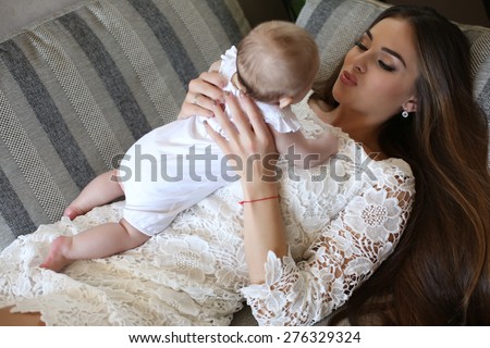 tender photo of beautiful mother with luxurious dark hair and her cute  little baby
