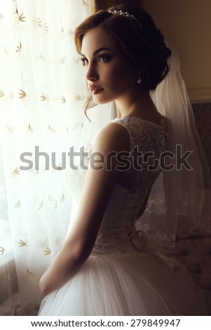 fashion interior photo of beautiful elegant bride with dark hair in luxurious wedding dress