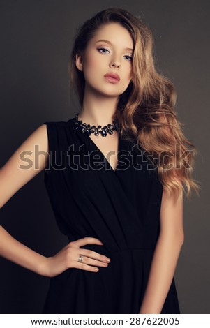fashion studio photo of beautiful young girl with dark natural hair wearing black dress and bijou