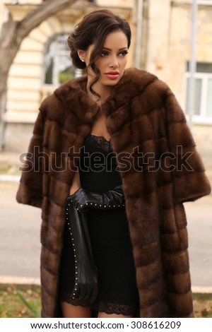 fashion outdoor photo of sexy glamour woman with dark hair wearing luxurious fur coat and leather gloves,posing  in autumn park