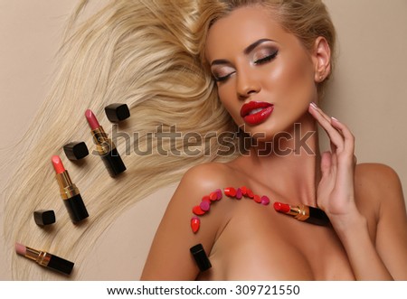 fashion studio portrait of sexy beautiful woman with blond hair and bright makeup posing with lipsticks