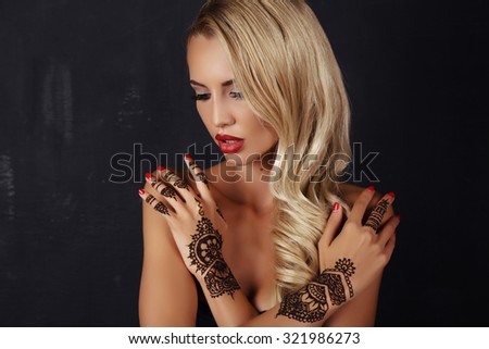 fashion studio photo of beautiful sensual girl with blond hair with henna pattern on hands