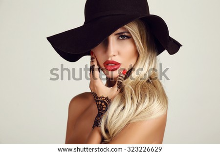 fashion studio portrait of beautiful sensual woman with blond hair with evening makeup and henna tattoo on hands