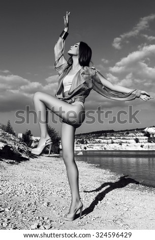 fashion black and white  outdoor photo of beautiful model with dark hair wears elegant suit, posing beside a lake