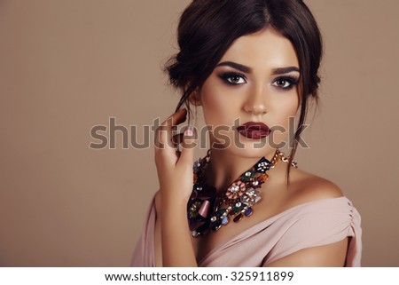 fashion studio portrait of beautiful young woman with elegant hairstyle and luxurious necklace