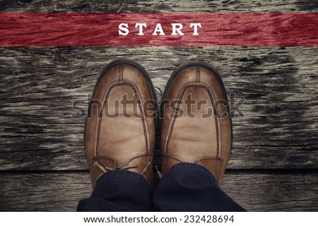 A business man is looking down at his feet with a red race line that says start here