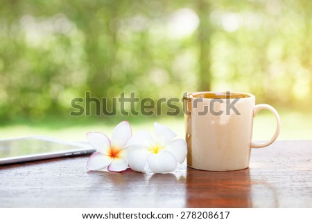 Coffee with flowers and tablet on wooden table