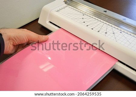 Worker laminating pouches with a pink sheet inside on an office table. Foto d'archivio © 