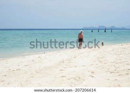 The old man walk the dog on the beach