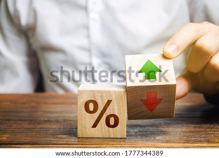 Businessman holds wooden blocks with percent and up or down arrow. Mortgage and loan rates. Interest rate, stocks, ranking. Business and finance concept. ストックフォト © 