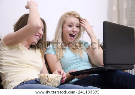 Girls laughing out loud, while watching something on a laptop.