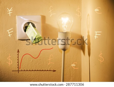 High electric bill concept, euros in power socket, light bulb, increasing graphic chart and world currencies. High contrast image, selective focus on light bulb and bill