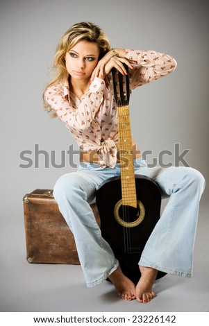 Studio portrait of a beautiful sexy young woman with black guitar