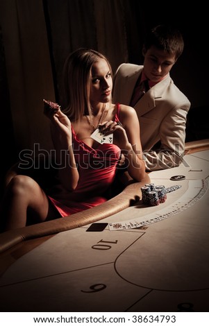 Young man & woman playing poker in casino