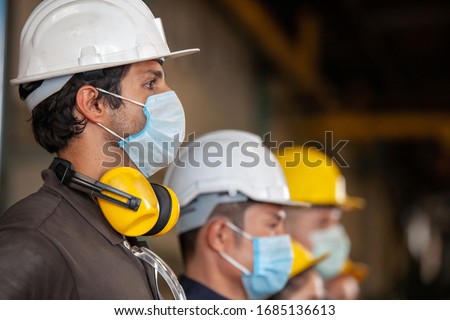 Workers wear protective face masks for safety in machine industrial factory.