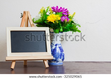 with empty blackboard and on wooden table over wall grunge background