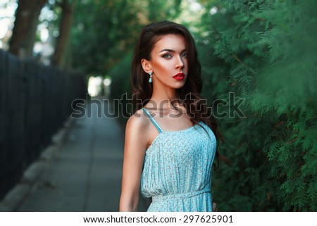 Beautiful fashion woman walking in the park in a turquoise dress.