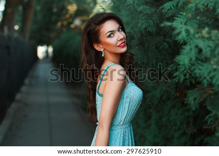 Fashion portrait of a beautiful smiling girl in a turquoise dress in the park.