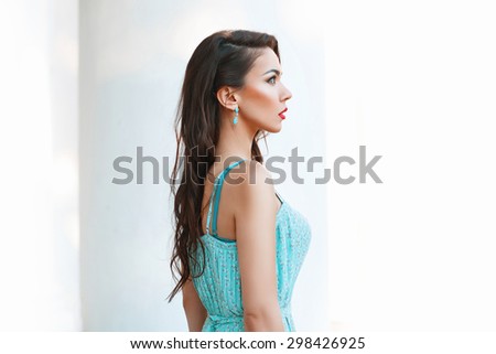 Portrait of a young pretty woman with turquoise dress on a white background. Profile Face