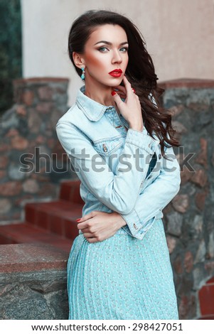 Beautiful pretty woman in a denim jacket and turquoise dress near stone