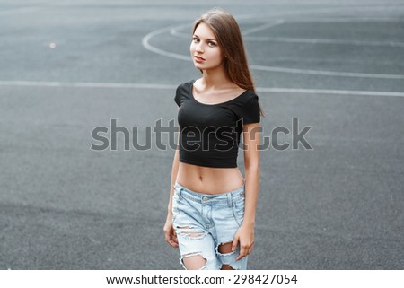 Pretty woman in a black T-shirt and torn jeans on the background of the stadium
