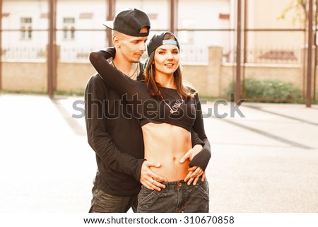 Young couple in a stylish black dress with a baseball cap.