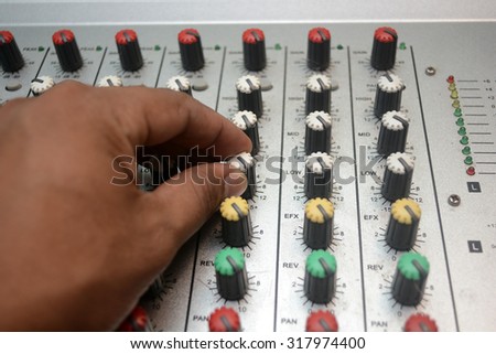 Part of an audio sound mixer with buttons and sliders and hand