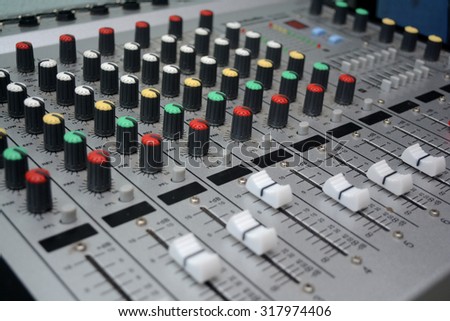 Detail of a music mixer desk with various knobs or slides. shallow depth of field