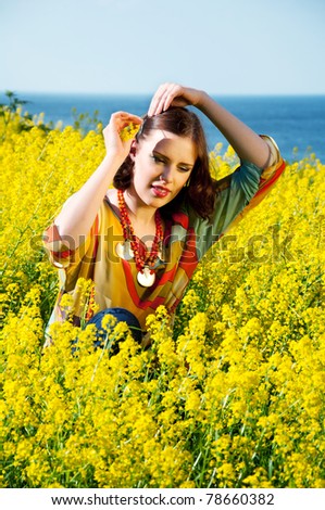 Young happy woman sitting in yellow flowers