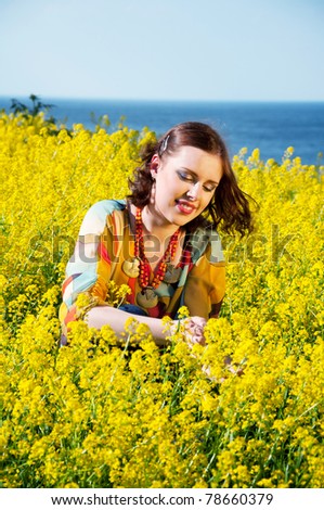 Young happy woman sitting in yellow flowers