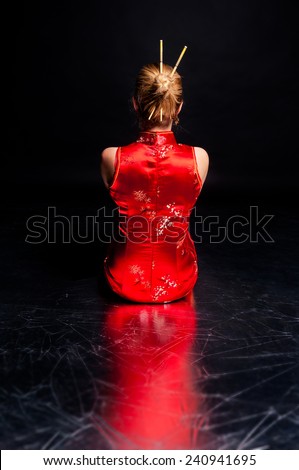Beautiful bright asian style woman sitting turned back in the darkness alone