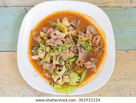 Fried basil pork with chili and cow pea slice in white plate on wood background .Thai food. Traditional food of Thailand. select focus.