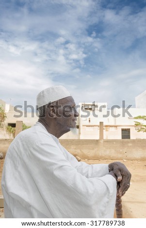 African old man sitting in front of his house, eighty years old