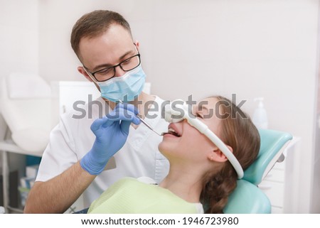Professional dentist examining teeth of young girl, using inhalation sedation mask on her Stock foto © 