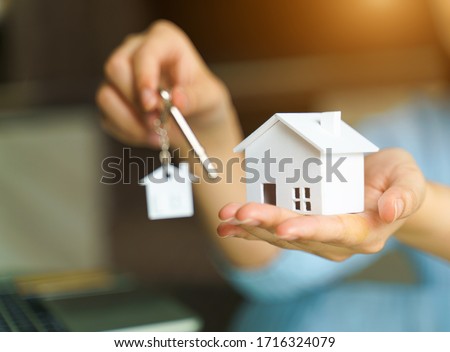 Woman holding white house model and house key in hand.Mortgage loan approval  home loan and insurance concept. Foto stock © 