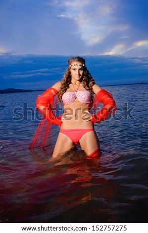 The girl in a red bathing suit jumps out of the sea