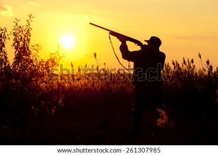 Rifle Hunter Silhouetted in Beautiful Sunset. Summer.