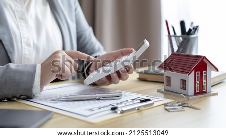 Selling a house with insurance, Salesperson or a home broker calculating the price to offer a special promotion and free insurance for customers who purchase a model home. 商業照片 © 