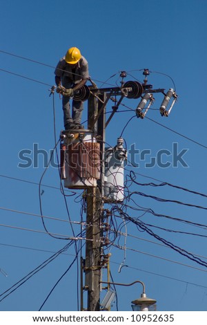 Electrician stays on the tower pole and repairs a wire of the power line